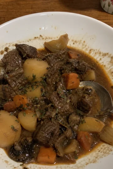 A steaming bowl of Beef and Guinness Stew garnished with fresh parsley