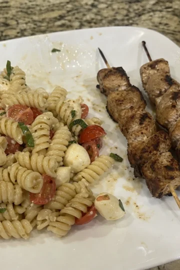 Colorful Caprese pasta salad with grilled chicken skewers