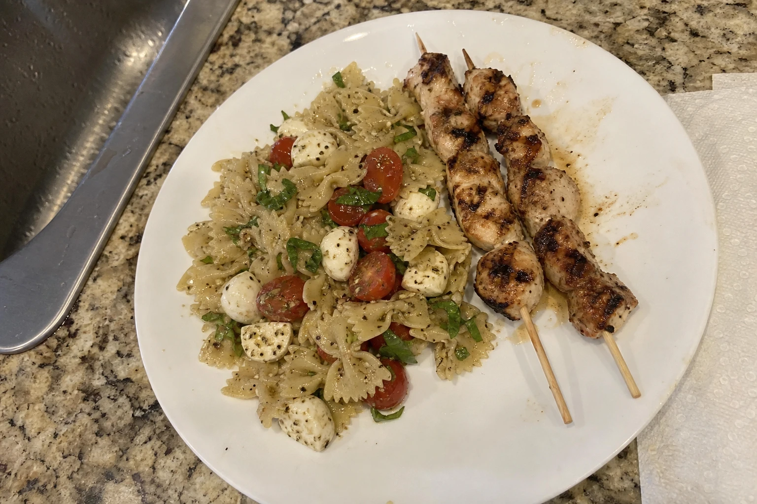 Bowl of Caprese pasta salad showing fresh basil and mozzarella