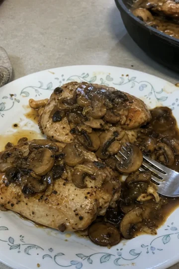 A warm plate of Chicken with Mushrooms garnished with fresh parsley and mushrooms.