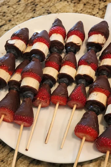 Colorful chocolate dipped fruit skewers arranged on a platter, ready to be enjoyed.