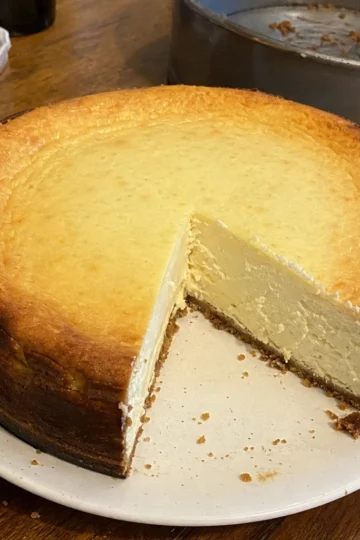 A slice of classic New York baked cheesecake with raspberry topping