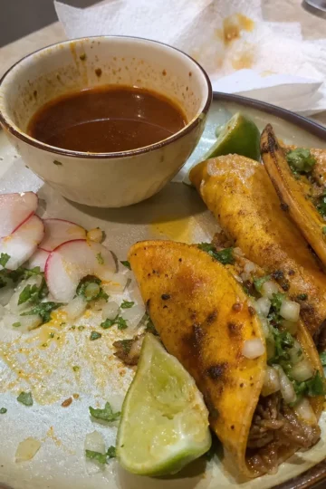 Plate of crock pot birria tacos topped with cilantro and onions