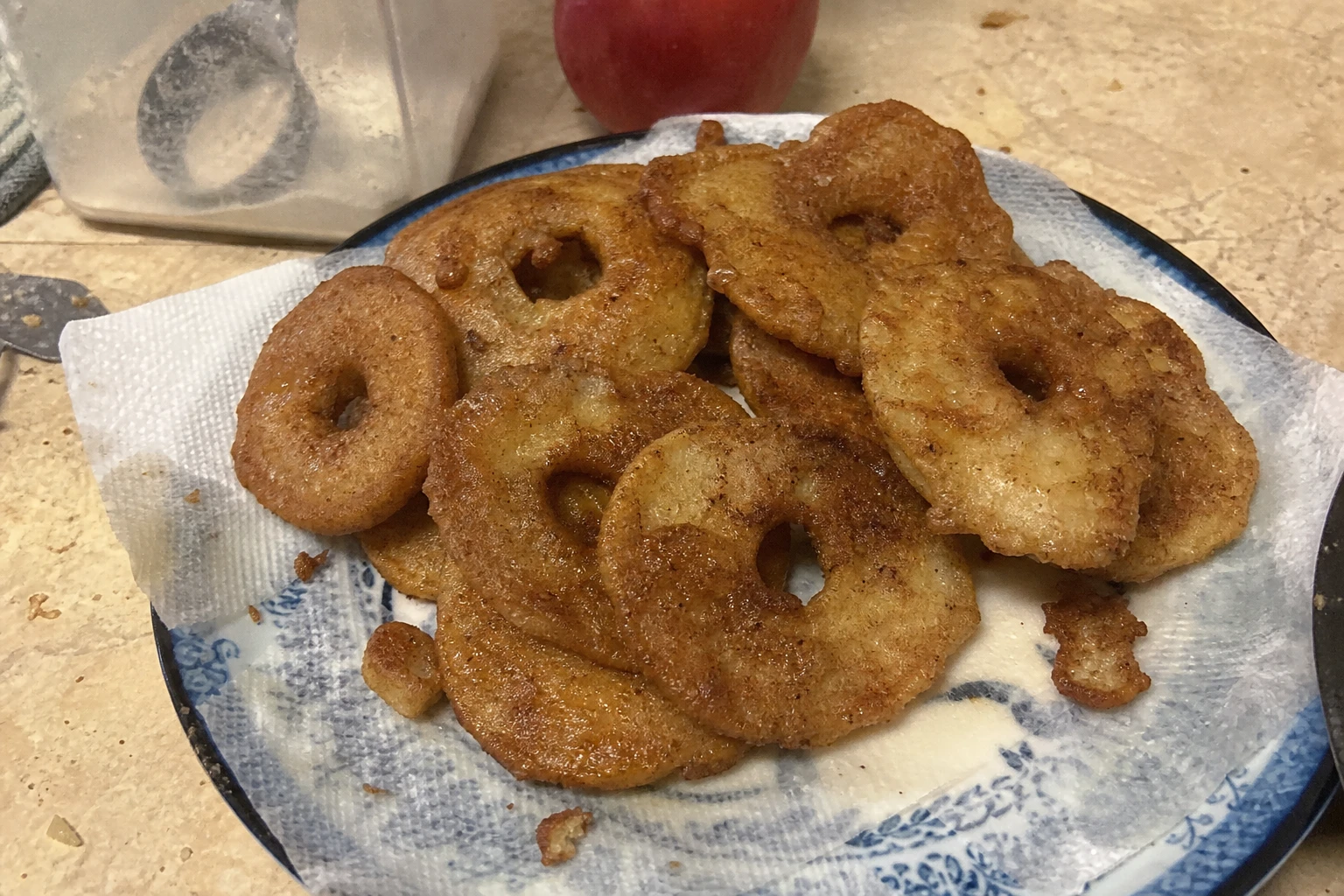 Golden brown apple rings being fried in a pan with bubbling oil.