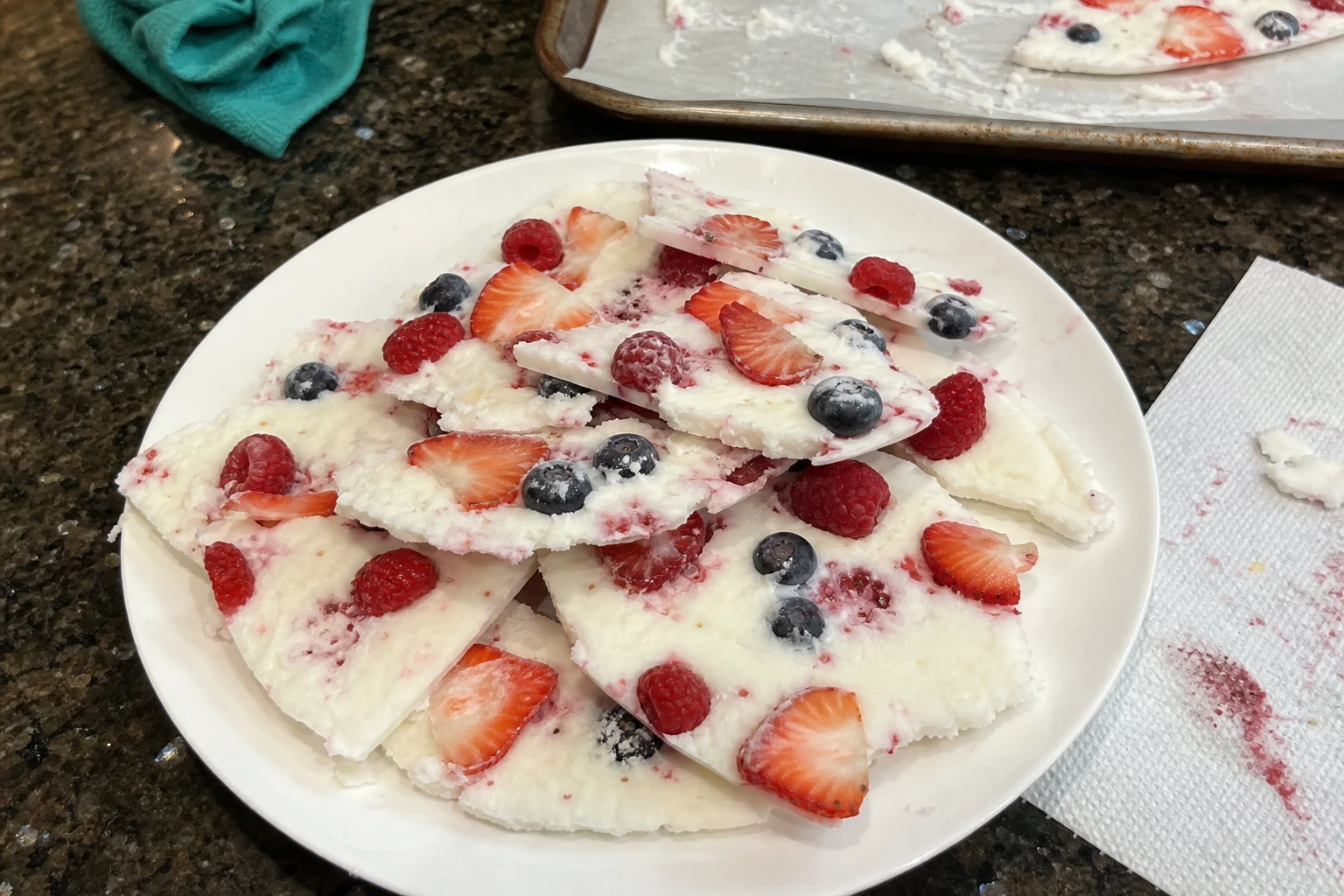 A close-up of vibrant yogurt bark pieces scattered on a rustic surface.