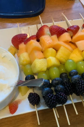 Colorful rainbow fruit skewers laid out on a rustic wooden table