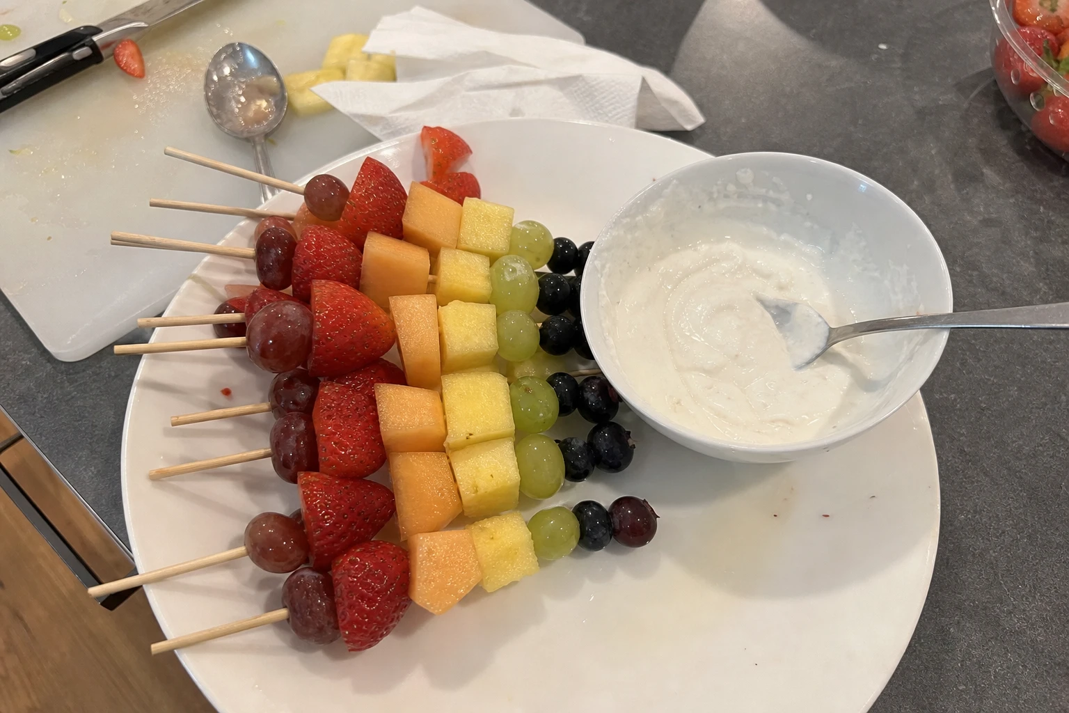 A vibrant plate of fruit skewers with a bowl of coconut dip