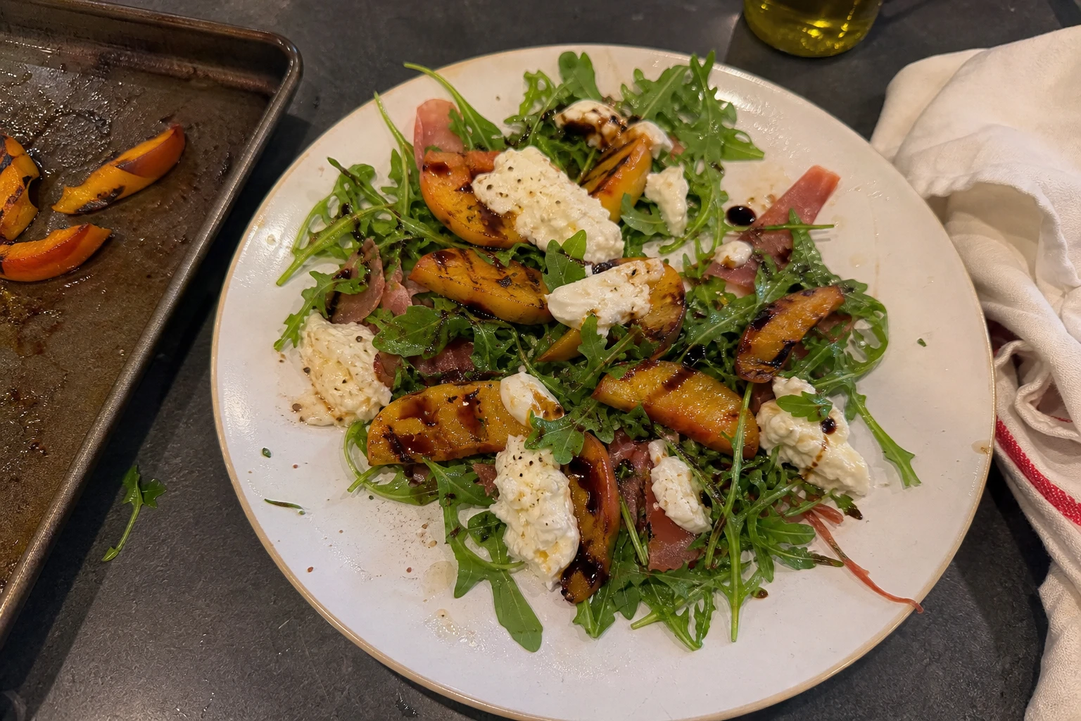 Close-up of creamy burrata cheese atop grilled peaches in a summer salad