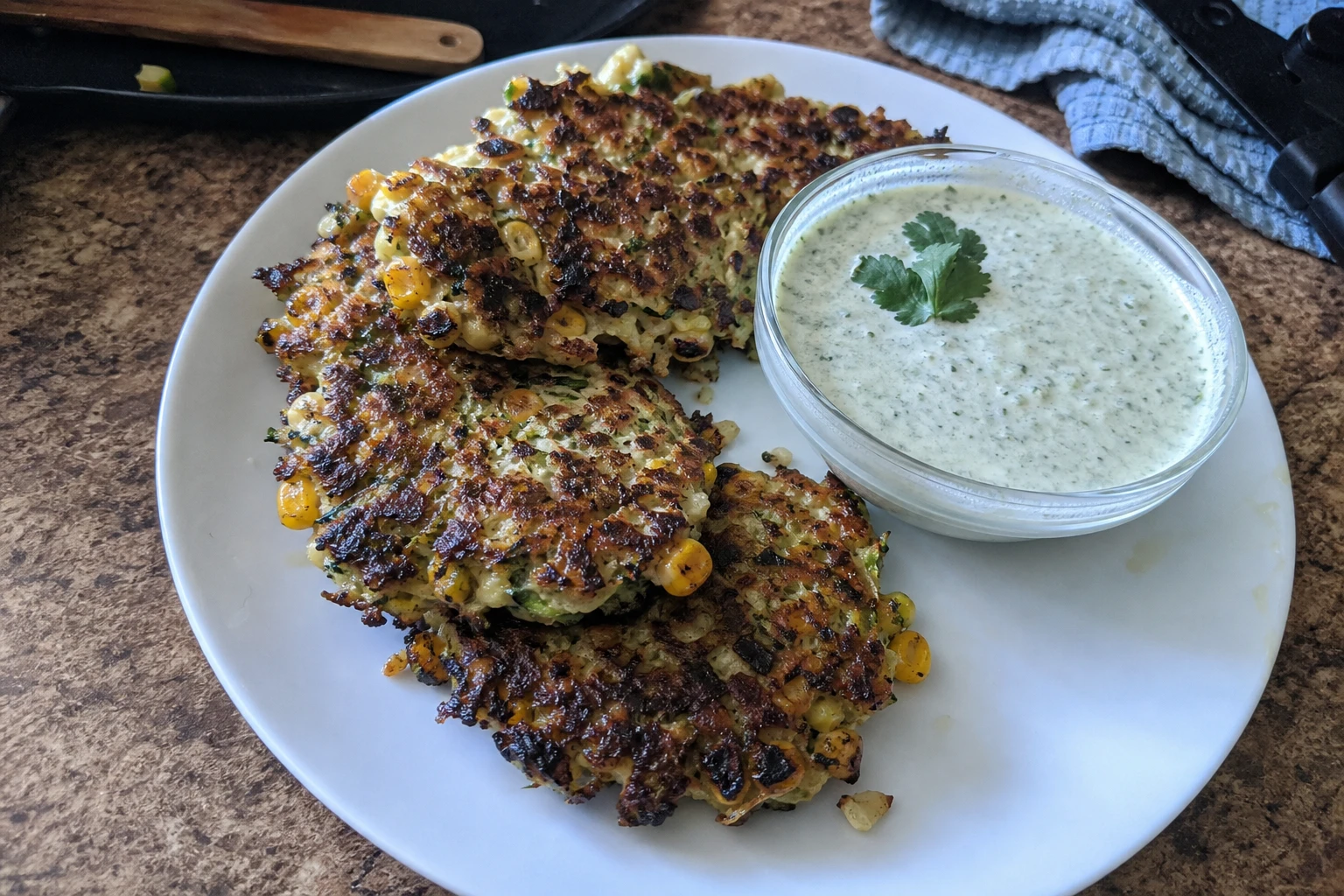 Cilantro lime dip served in a bowl next to fritters
