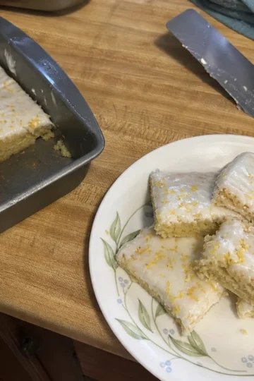 A plate of freshly baked lemon cake bars garnished with powdered sugar.