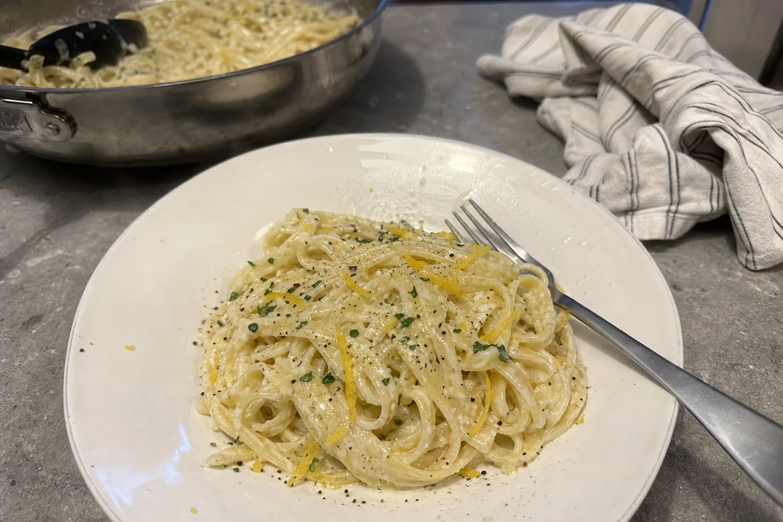 Close-up of creamy pasta with lemon zest and ricotta cheese.
