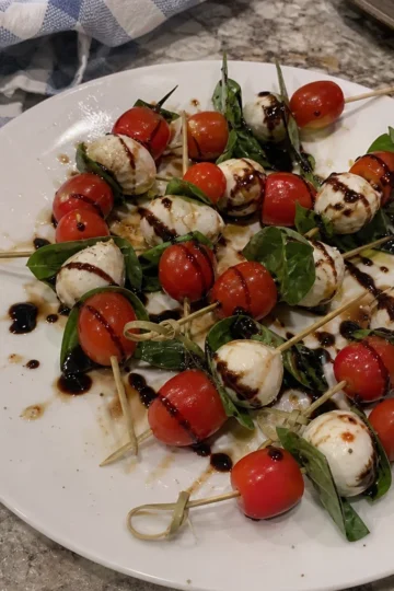 A platter of colorful mini caprese skewers with bright cherry tomatoes and fresh basil