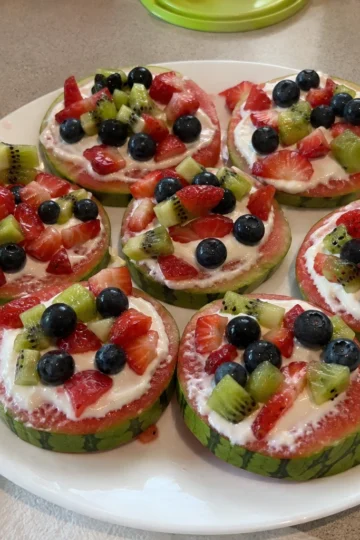 Brightly colored Mini Watermelon Pizzas with assorted toppings on a wooden table.