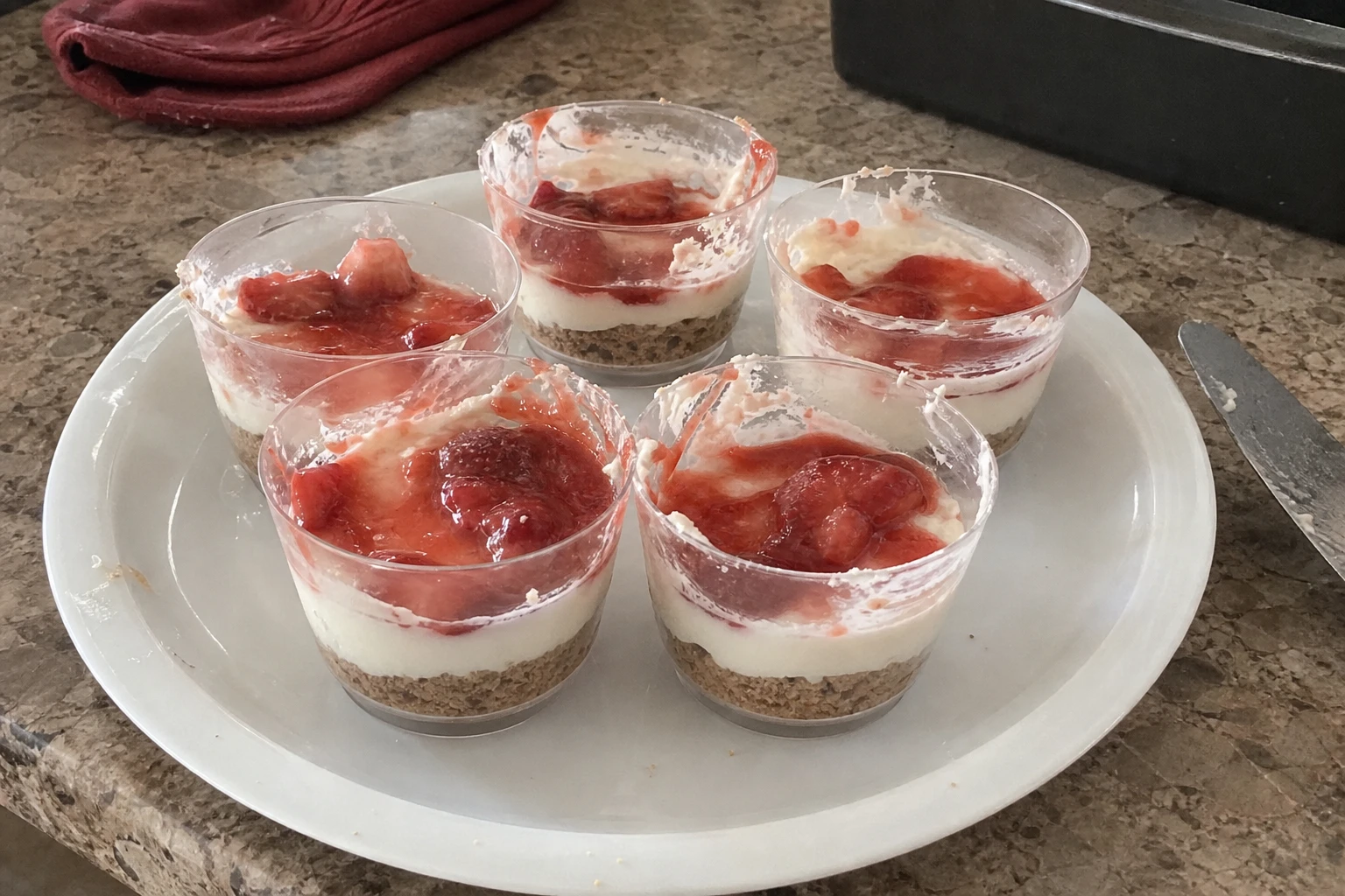 Close-up of a layered no-bake strawberry cheesecake cup with graham cracker crust