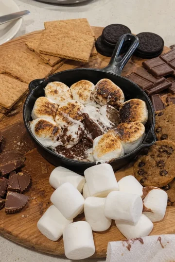 Beautifully arranged s'mores dessert board with chocolate, marshmallows, graham crackers, and fruits.