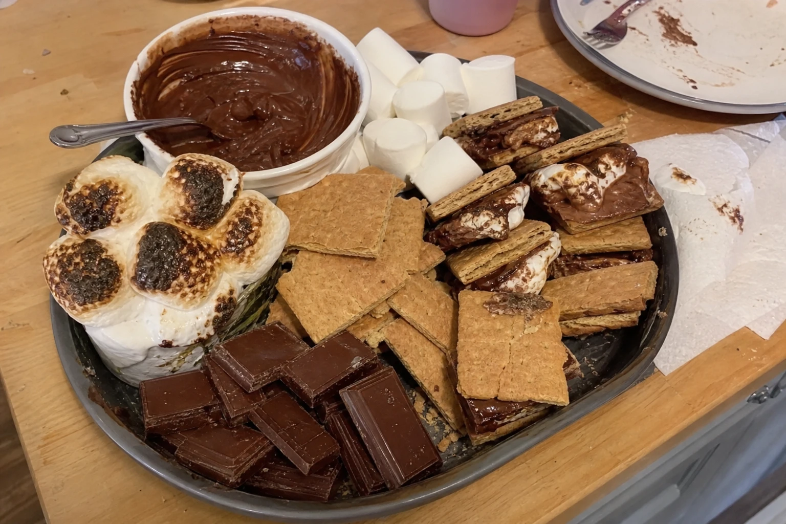 Close-up of marshmallows melting beside chocolate pieces on the s'mores board.