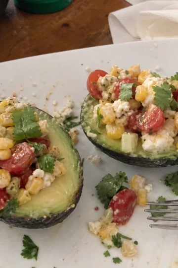 Stuffed avocado salad topped with colorful vegetables and cilantro.