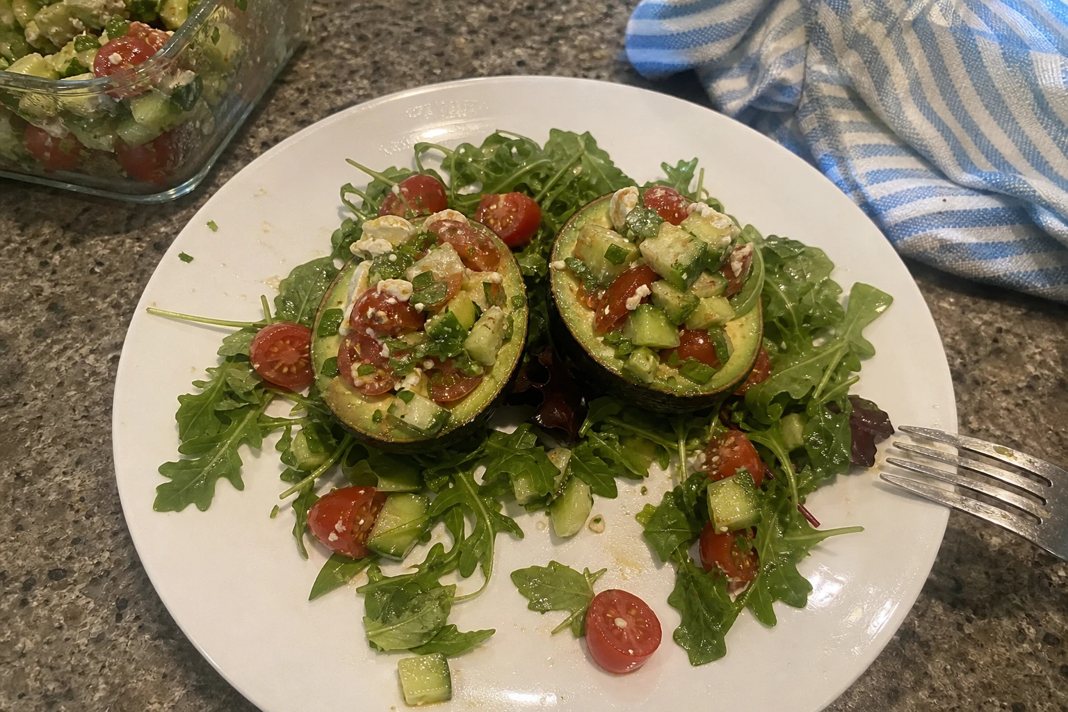 Close-up of an open avocado filled with fresh cucumber, tomato, and bell pepper.