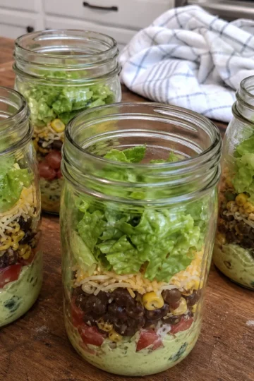 Mason jars filled with colorful taco salad ingredients