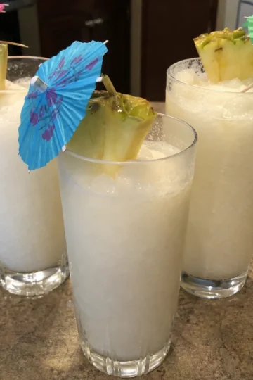 Tropical coconut rum slushie garnished with pineapple and mint.