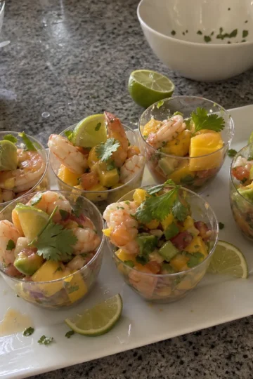 Colorful mango shrimp ceviche cups garnished with avocado