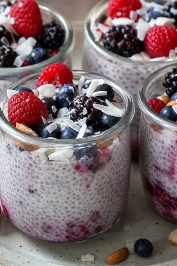 A vibrant berry coconut chia pudding topped with fresh berries and mint leaves.