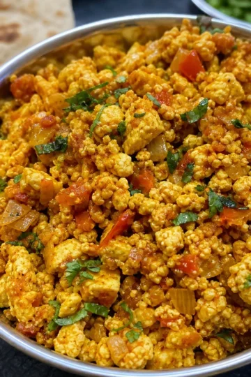 A warm bowl of paneer bhurji garnished with cilantro.