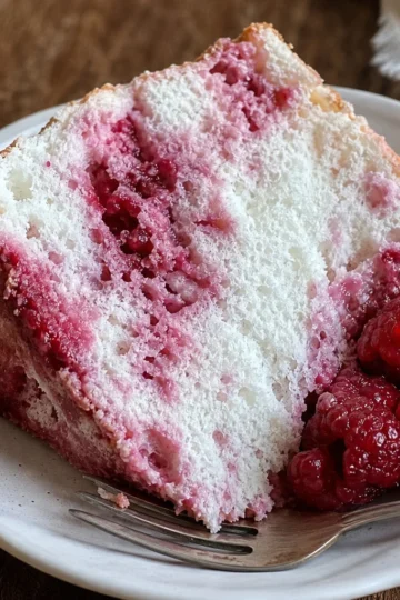Slice of Raspberry Angel Food Cake topped with fresh raspberries
